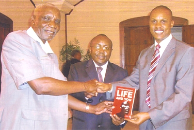 Costantine Magavilla is seen handing over his book to Mr Maembe (far left), a member of the Confederation of Tanzanian Industries (CTI) Governing Council and Mr. Wambugu Wa Gichohi, a Senior Trainer with Worldahead Centre after a Strategic Leadership